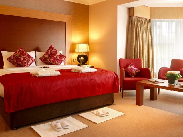 chambre lit fauteuil rouge coussins rideaux beige lampe 