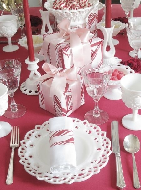 décoration-table-Noël-nappe-rouge-assiettes-blanches-boîtes-cadeaux-rubans-roses décoration de table pour Noël