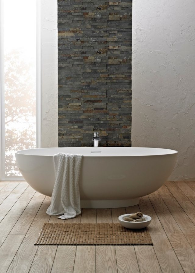 tapis-salle-bains-petit-marron-baignoire-ovale-mur-pierre-décorative