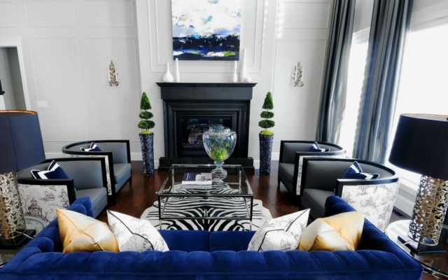 salon intérieur moderne tableau déco idée coussins beige table de salon en verre fauteuil design coussins bleus cheminée plante déco murs blancs