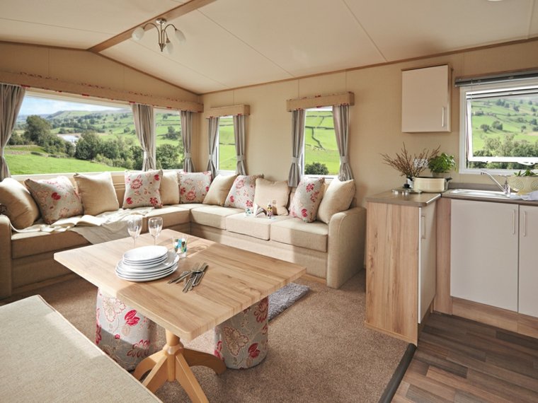 intérieur caravane aménagement table en bois canapé coussins tapis de sol beige