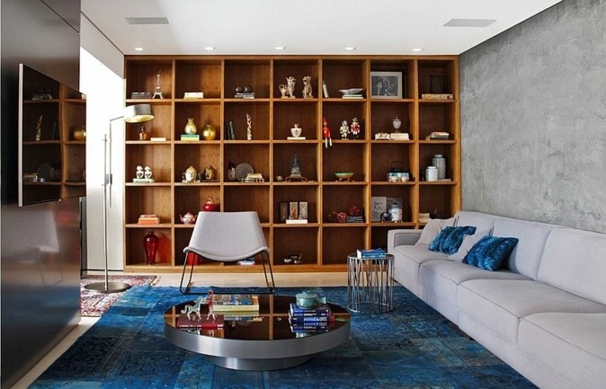 appartement design idée aménagement canapé gris coussin bibliothèque bois étagères tapis de sol bleu table basse