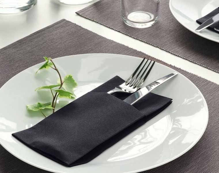 pliage serviette en papier dans assiettes avec couverts noir