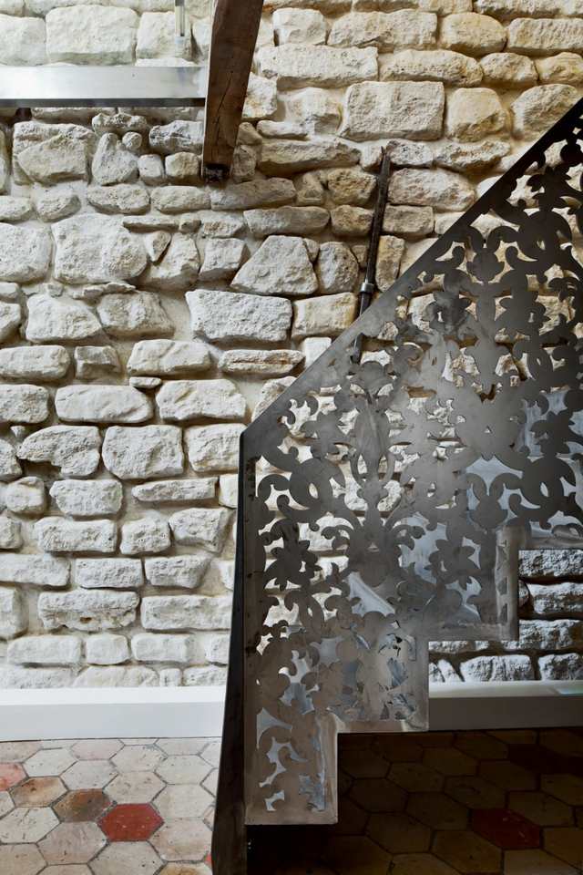 Beau escalier en fer forgé et mur en pierre  briques calcaire blanches 